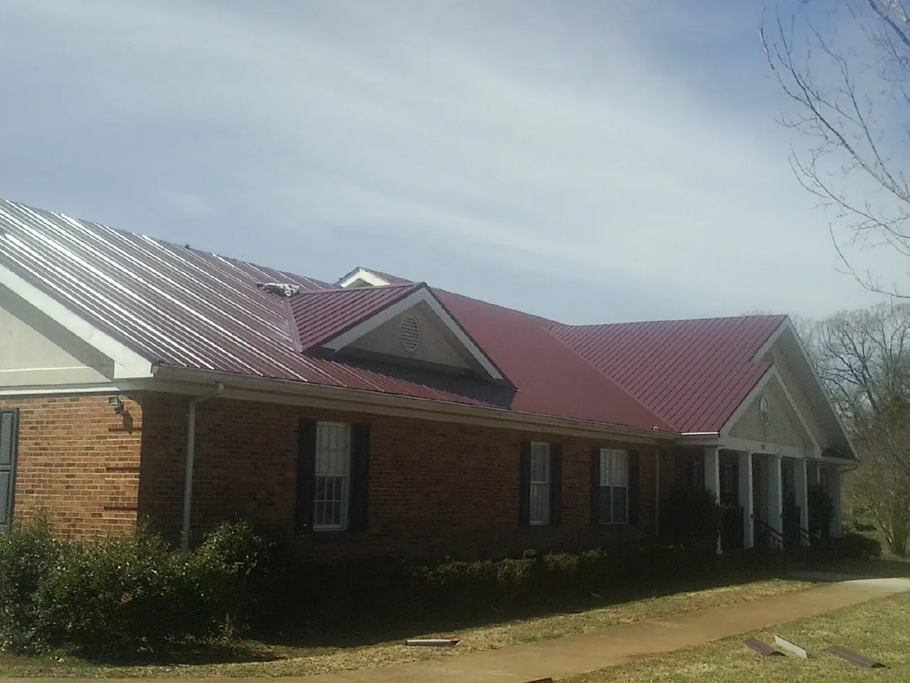 Red metal roof with gabled entries on a long brick building in Clio