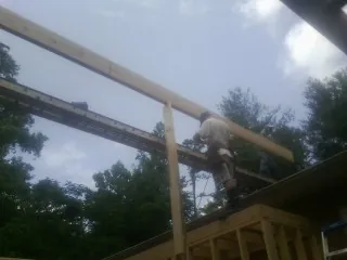 Carpenter setting a ridge beam over a new addition frame — Ice Dam Removal by Roofing Brothers in Clio